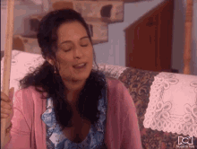 a woman in a pink sweater sits on a couch with nuestra tele written on the bottom