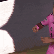 a man in a pink adidas jersey is dancing in front of a large screen