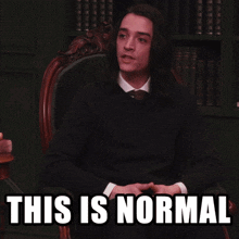 a man sitting in a chair with the words " this is normal " on the screen