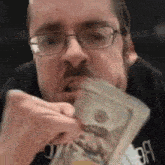 a man with glasses is eating a stack of money .
