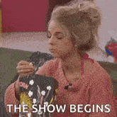 a woman is eating popcorn while sitting on a couch and says `` the show begins '' .