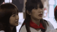 a woman with a red scarf around her neck is talking to two other women