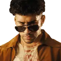 a man wearing sunglasses and a brown jacket looks serious