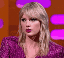 a close up of a woman 's face with a purple shirt on .