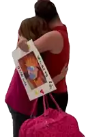 a woman is hugging another woman who is holding a sign that says welcome to iowa