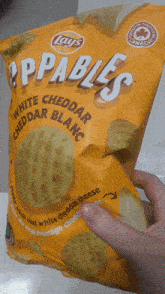 a person is holding a bag of appables white cheddar cheddar blanc