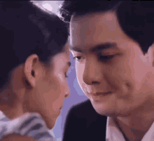 a man and a woman are touching their foreheads in a close up .