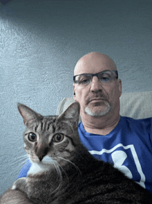 a man with glasses is holding a cat in his lap