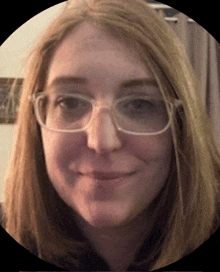 a woman wearing glasses looks at the camera and smiles