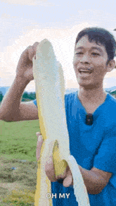 a man in a blue shirt is holding a very long banana in his hands .