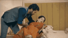 a man is standing next to a woman laying on a bed in a bedroom .