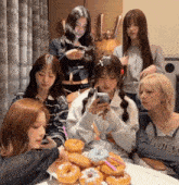 a group of girls are sitting around a table with donuts