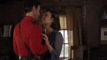 a man in a red uniform kisses a woman with the name andrew coppin written below them
