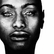 a black and white photo of a man crying with a tear running down his cheek .