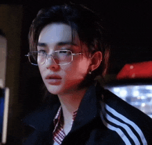 a young man wearing glasses and a black jacket .
